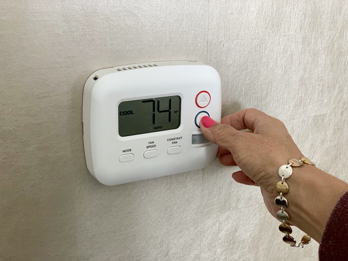 woman-setting-the-thermostat-to-keep-the-home-at-c-2022-11-11-16-52-08-utc